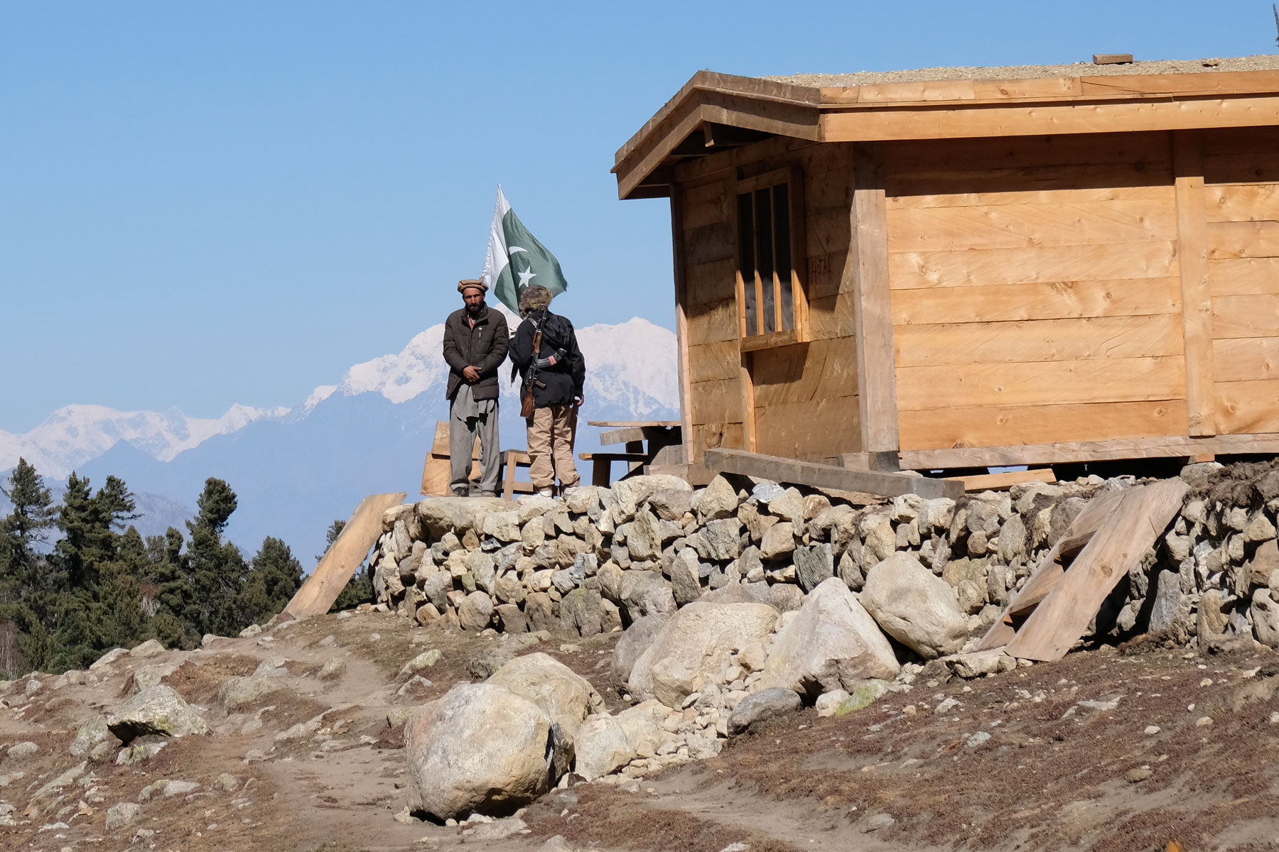 Zwei pakistanische Männer stehen neben einer Hütte im Baihal Camp.