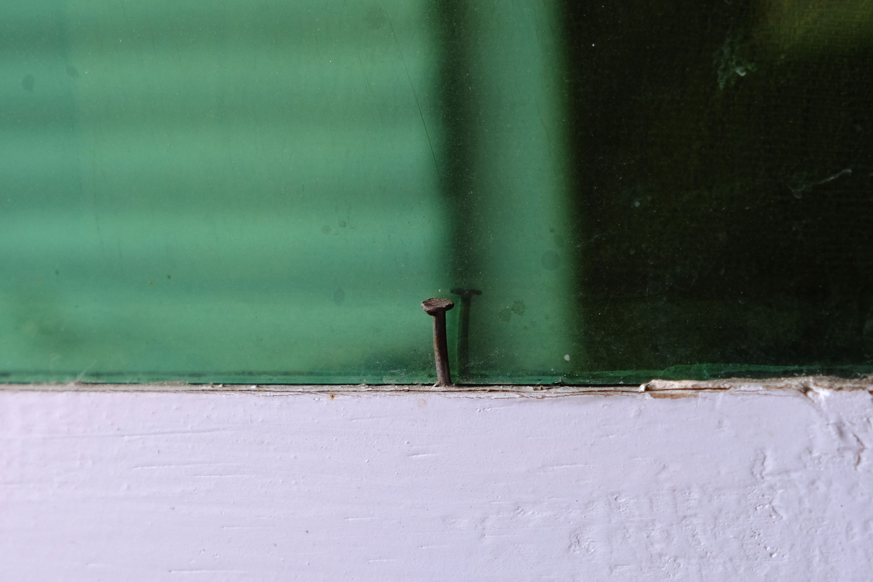 Eine Fensterscheibe, die mit einem Nagel befestigt ist.