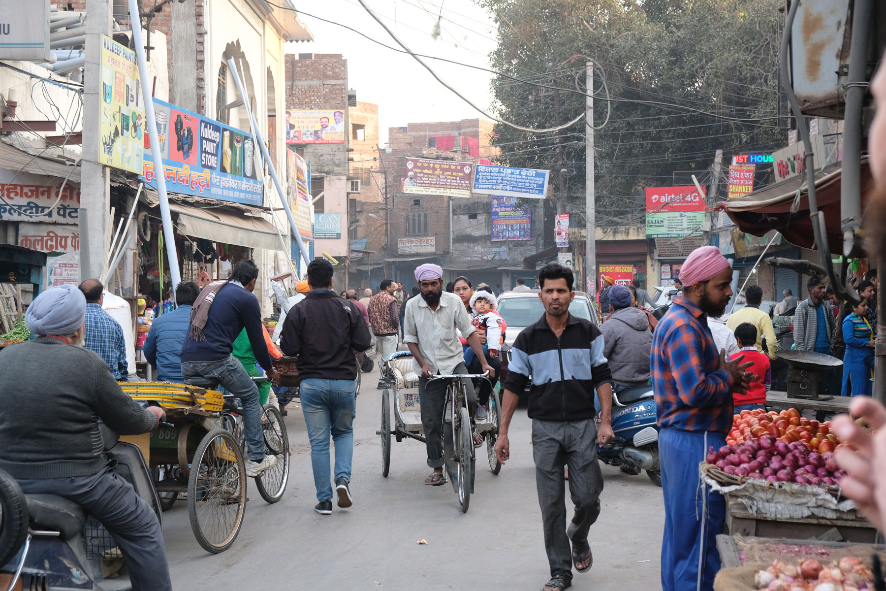 Menschen und Fahrradrikschas auf einer Straße in Amritsar.