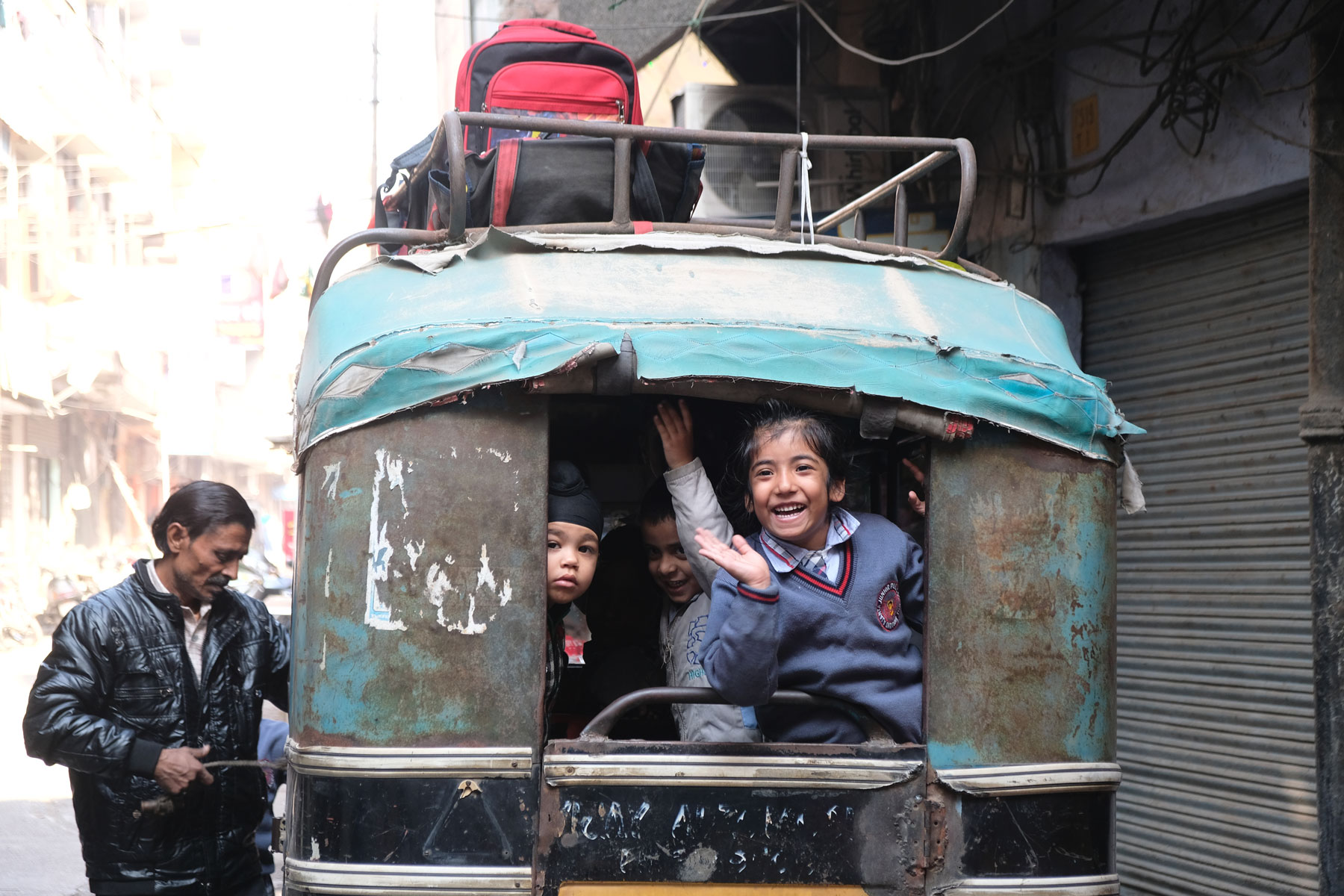 Schulkinder winken aus dem Fenster einer Rikscha in Amritsar.