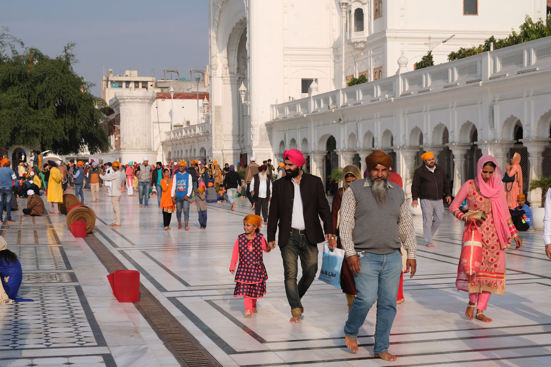 Menschen gehen auf weißem Marmor im goldenen Tempel in Amritsar.