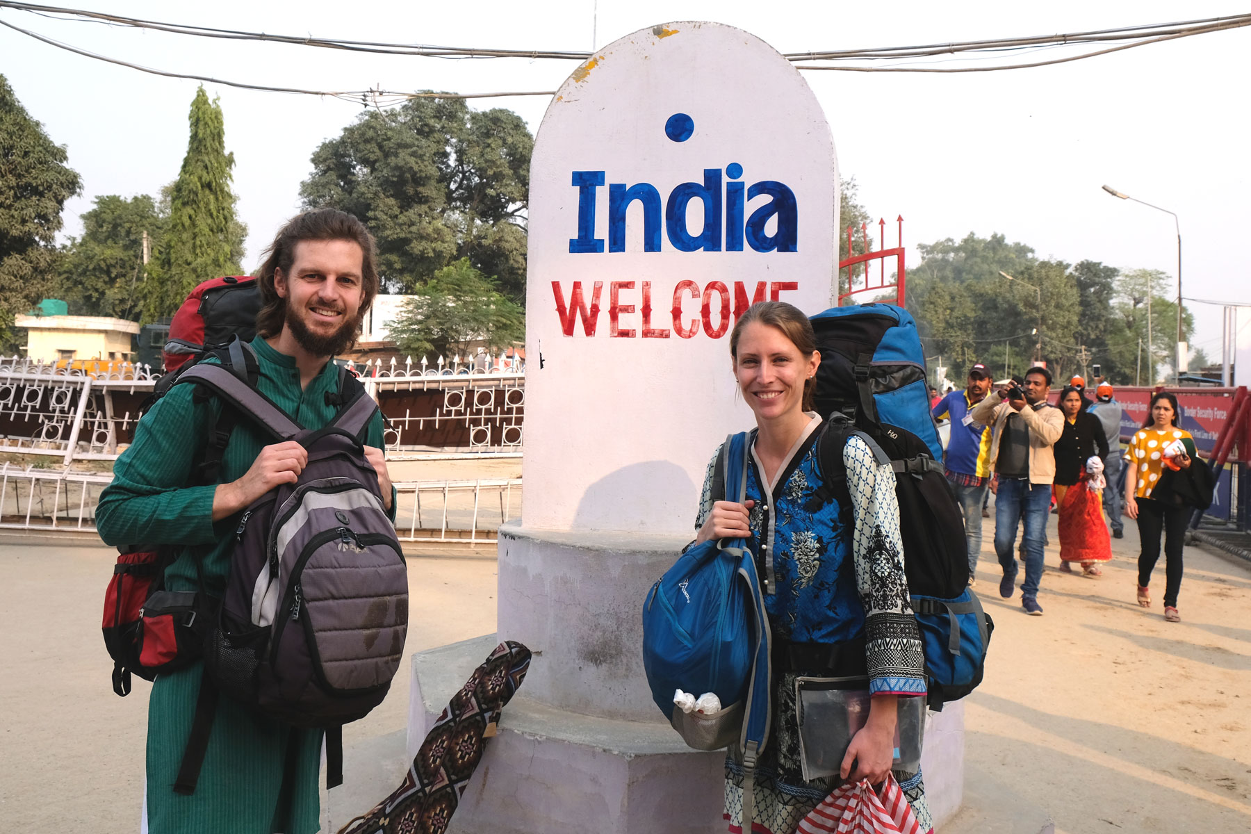 Sebastian und Leo mit Gepäck vor einem Monument mit der Aufschrift "India welcome".