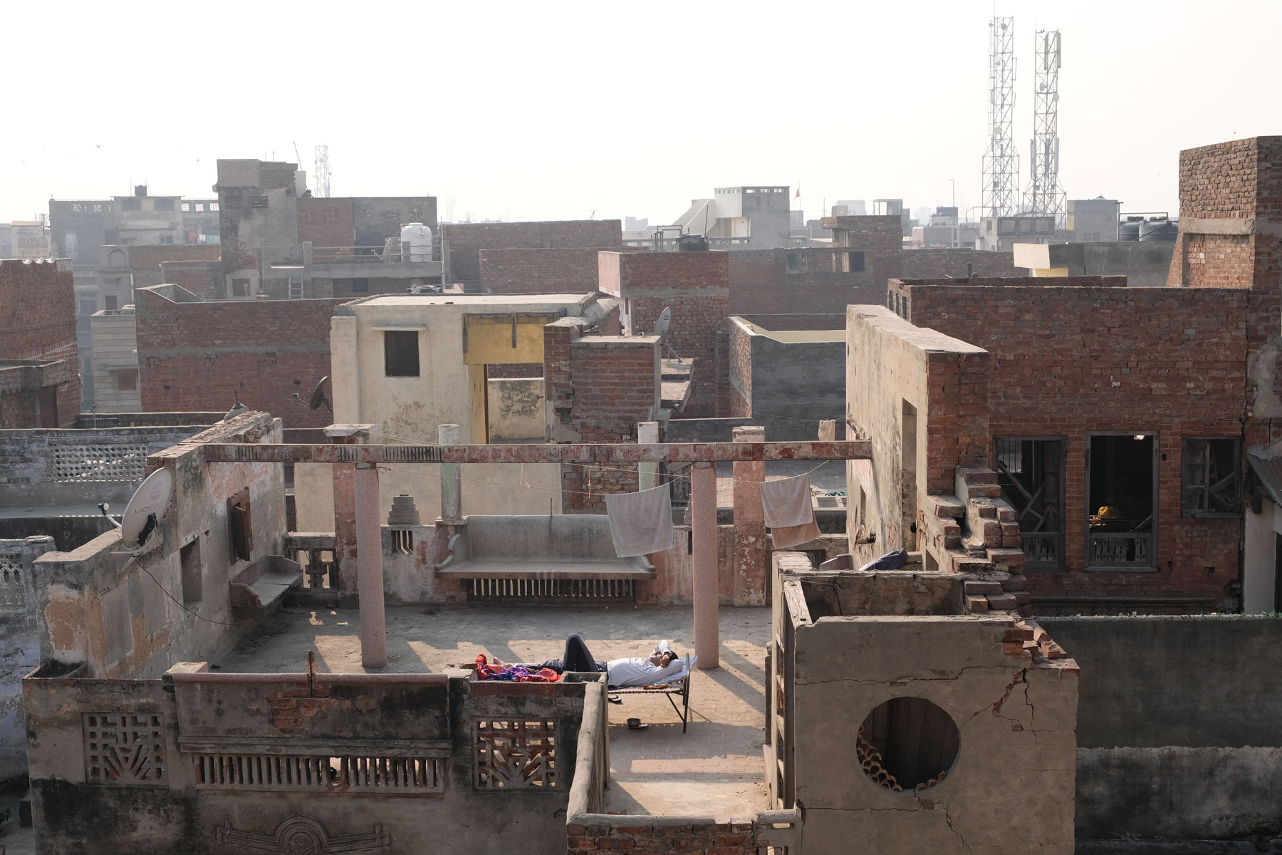 Ein Mann schläft auf einer Liege auf einer Dachterrasse in Amritsar.