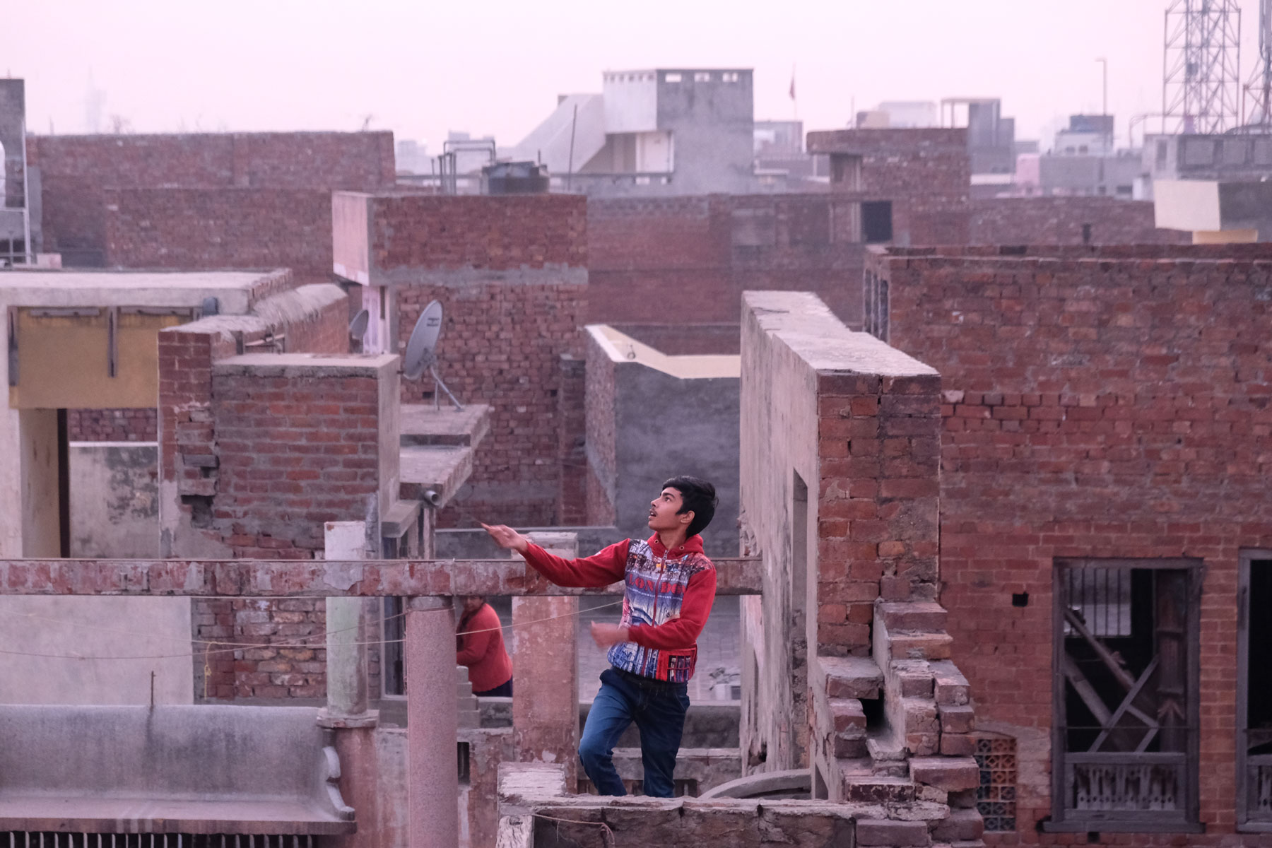 Ein indischer Junge auf einer Dachterrasse in Amritsar beim Drachensteigen.