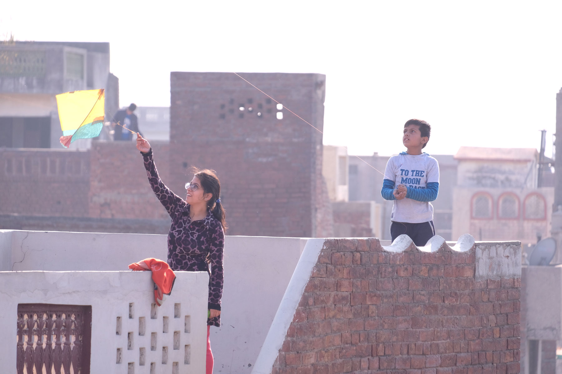 Zwei Kinder stehen auf einer Dachterrasse in Amritsar und lassen Drachen steigen.