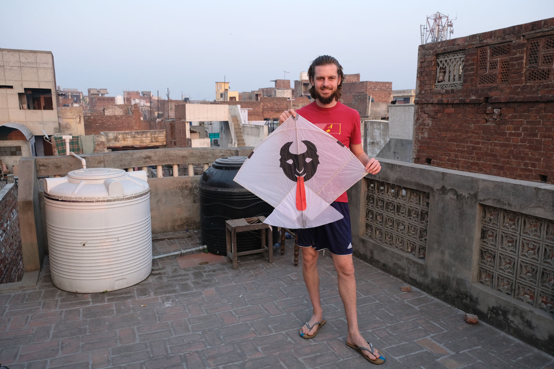 Sebastian steht auf einer Dachterrasse in Amritsar und hält einen Papierdrachen in der Hand.