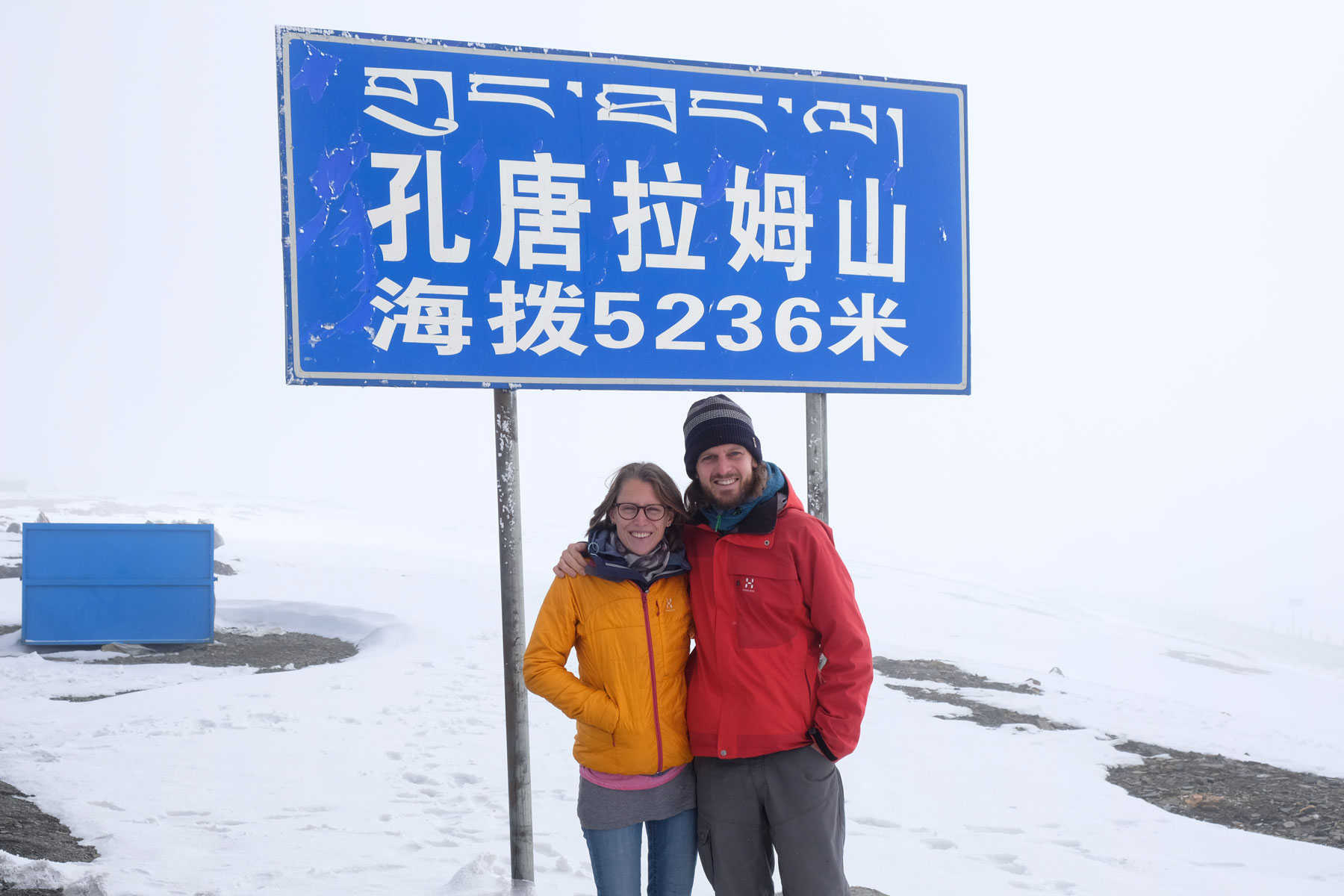 Leo und Sebastian stehen auf dem schneebedeckten Friendship Highway vor einem Schild mit der Aufschrift "5236".