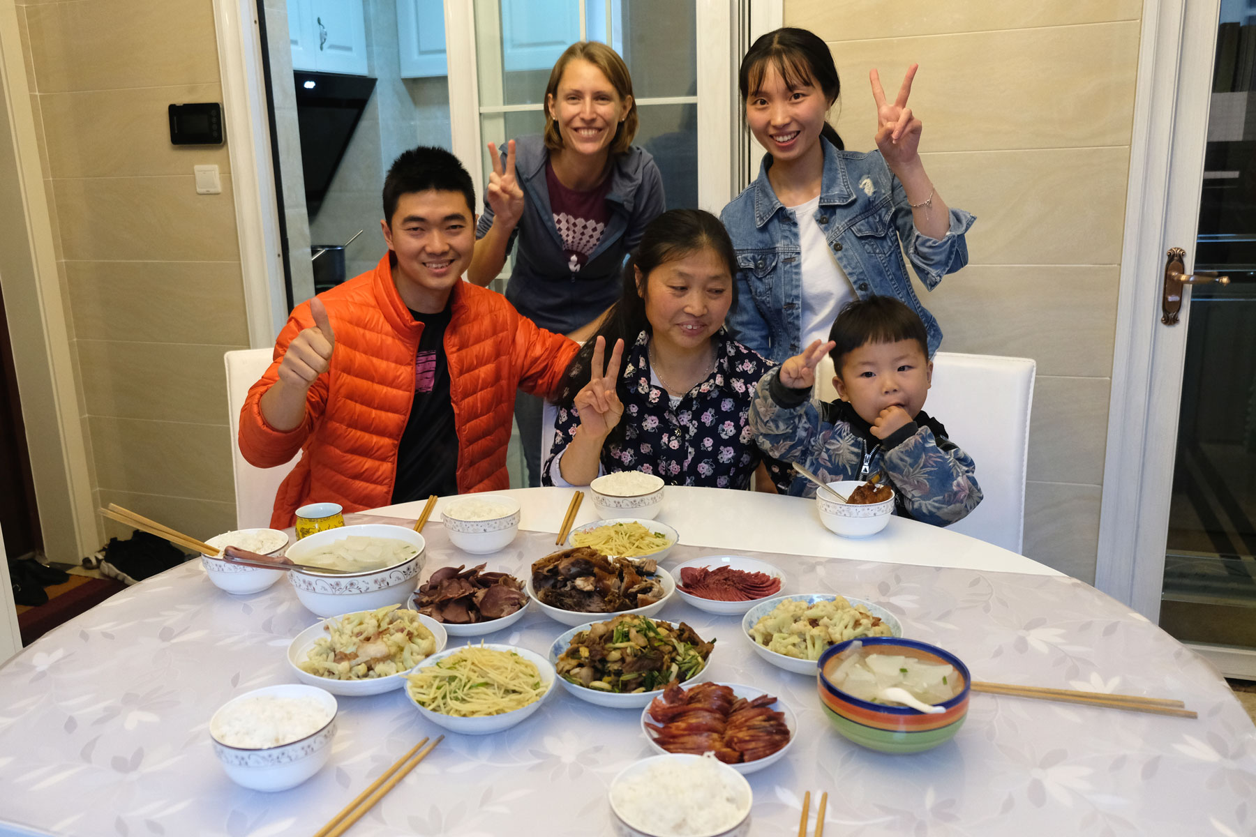 Leo mit einer chinesischen Familie vor einem gedeckten Tisch.