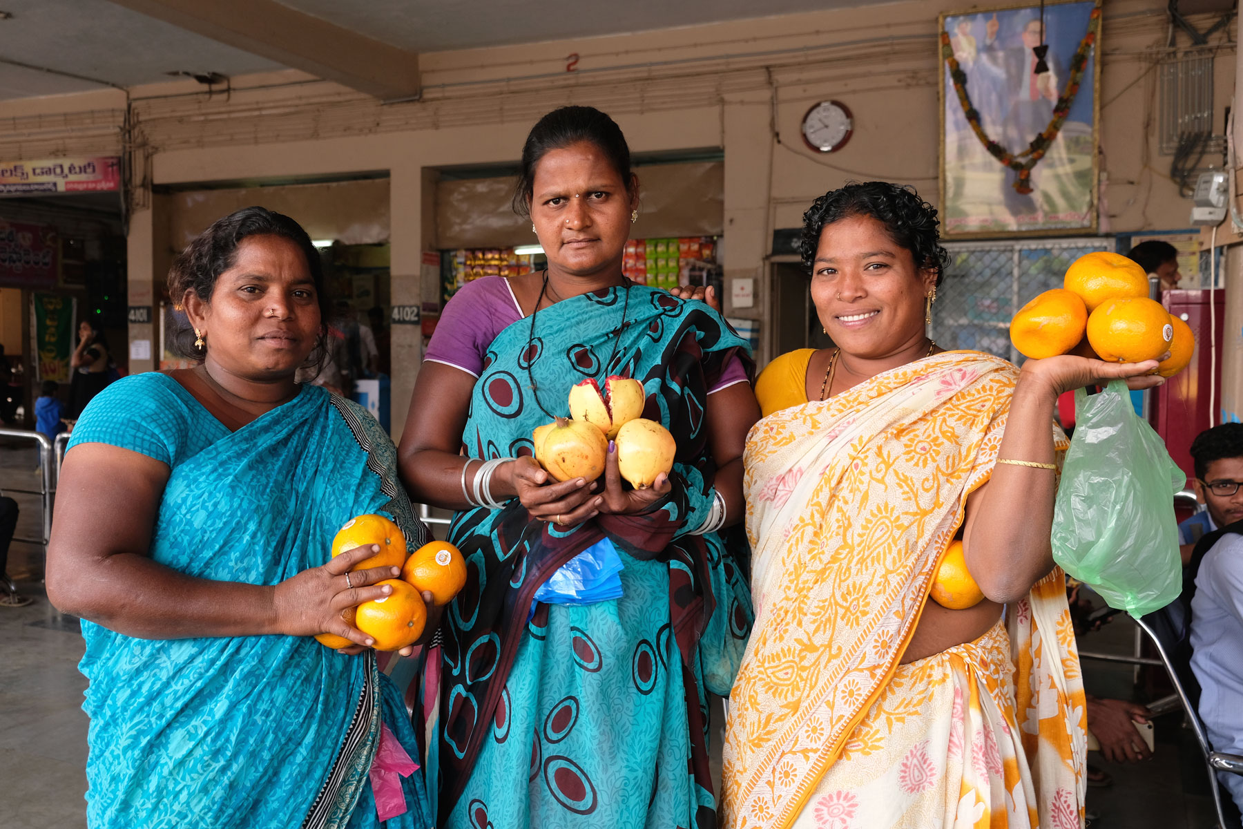 Drei indische Frauen halten am Busbahnhof von Vizianagaram Orangen in der Hand.