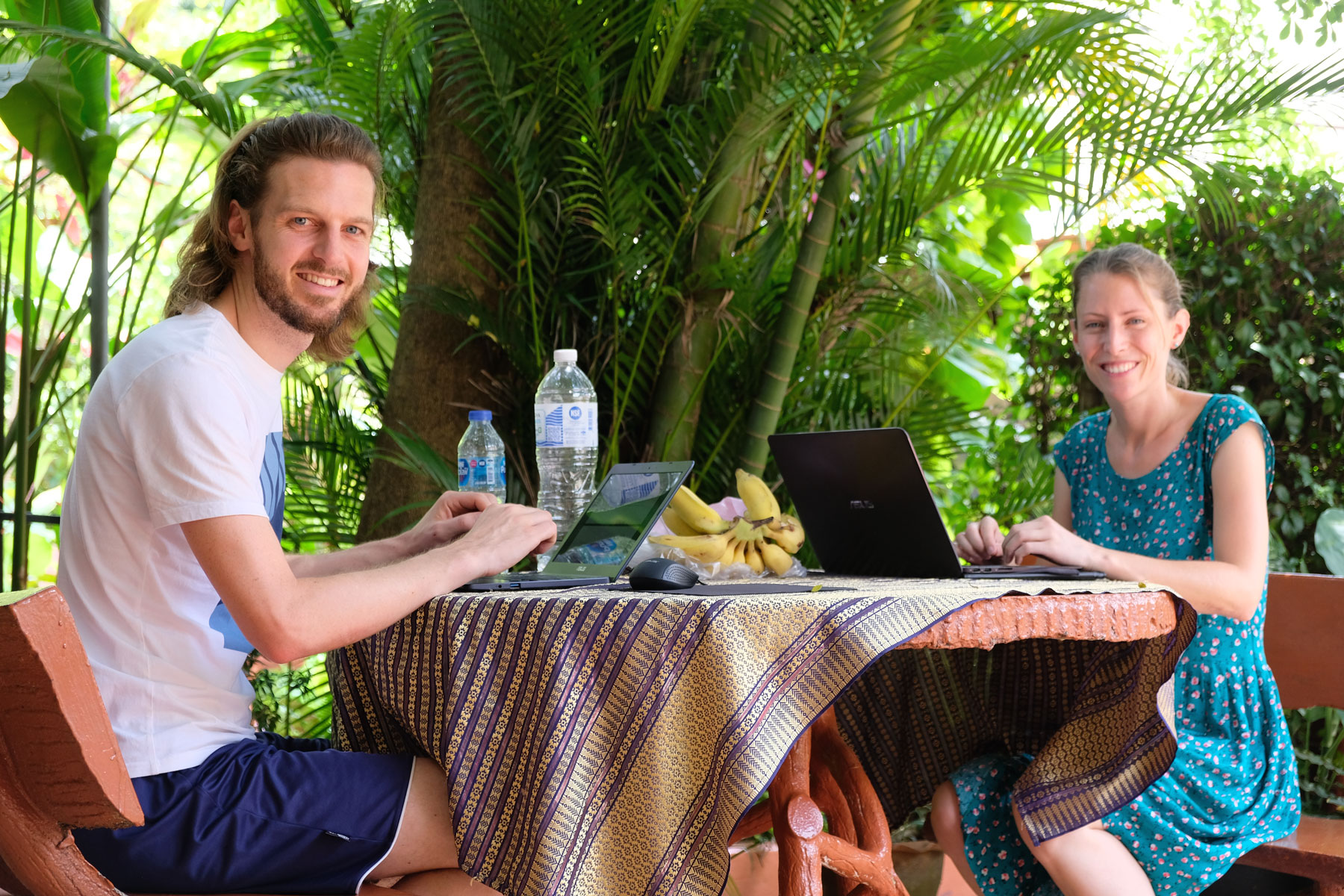 Sebastian und Leo sitzen an einem Tisch, auf dem ihre Laptops stehen.