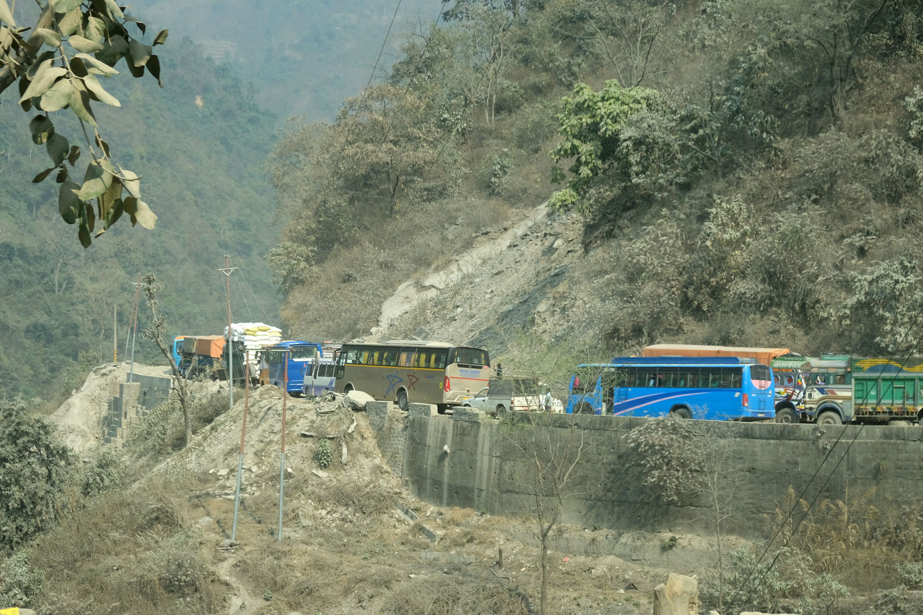 Busse und Lastwagen stehen im Stau auf einer Straße in Nepal.