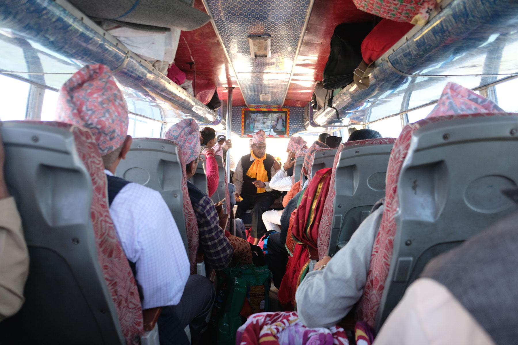 Nepalesische Pilger mit rosafarbenene Hüten in einem Bus.