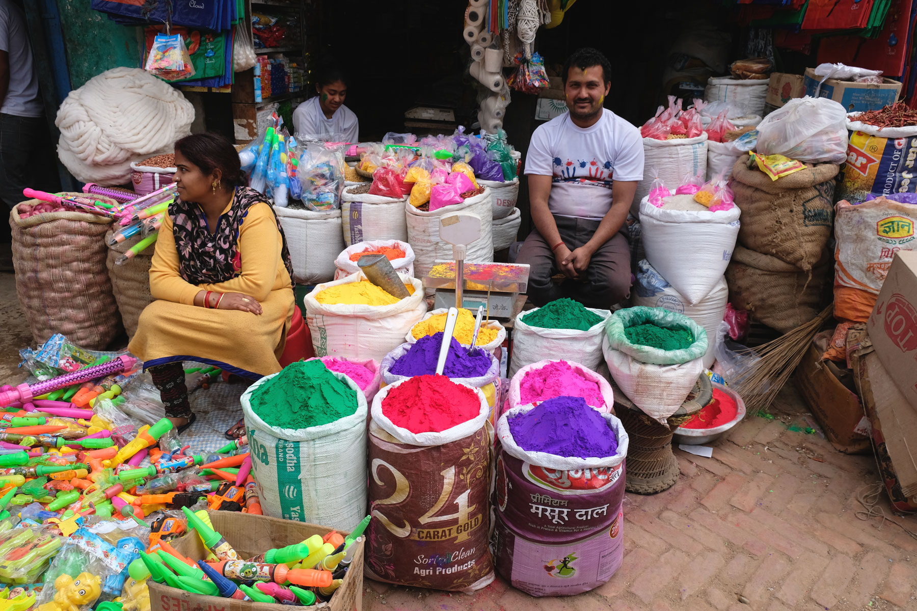 Zwei Verkäufer in Tansen mit Säcken voll buntem Farbpulver für das Holi-Fest.