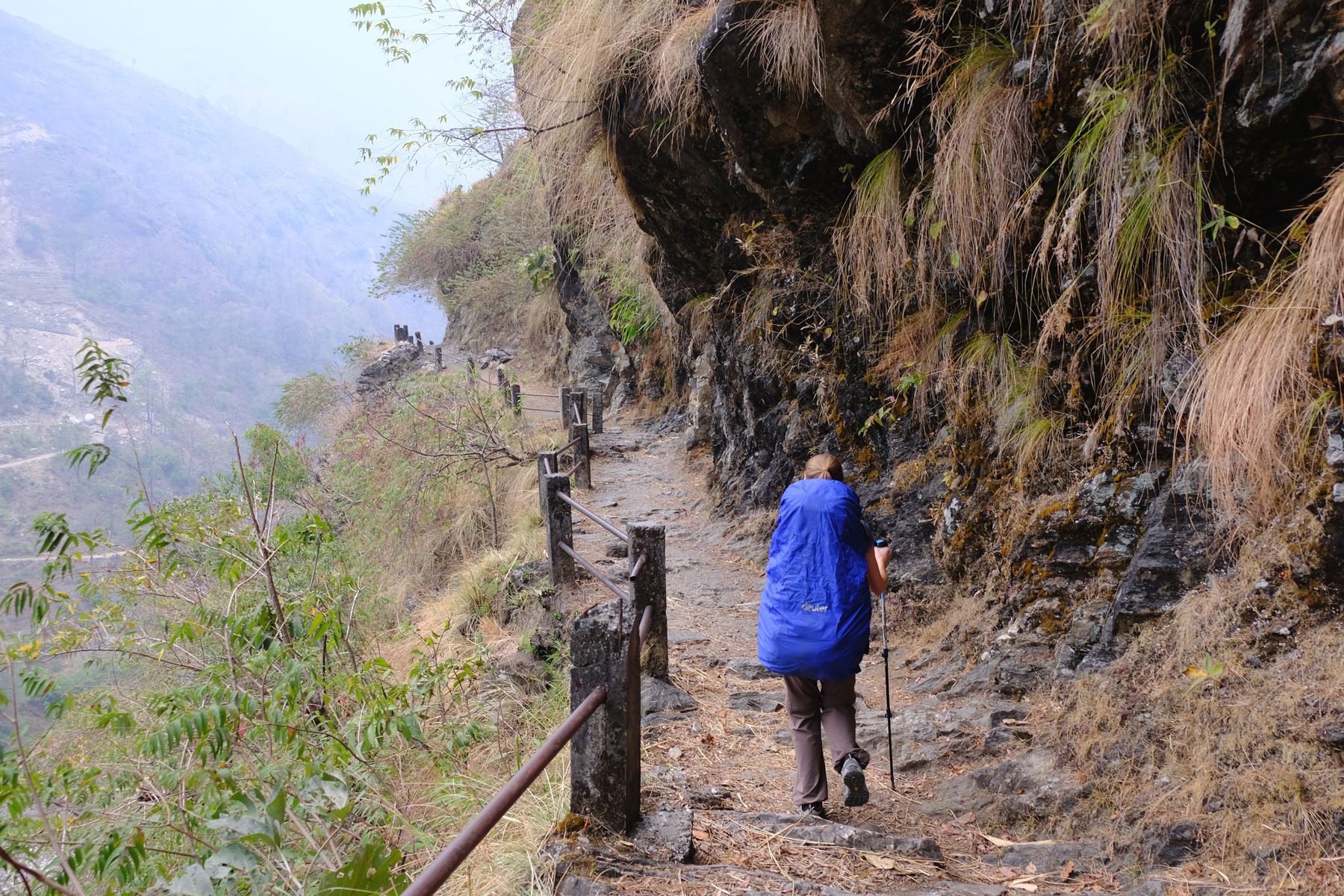 Leo wandert mit Rucksack und Regenschutz auf einem Wanderweg.