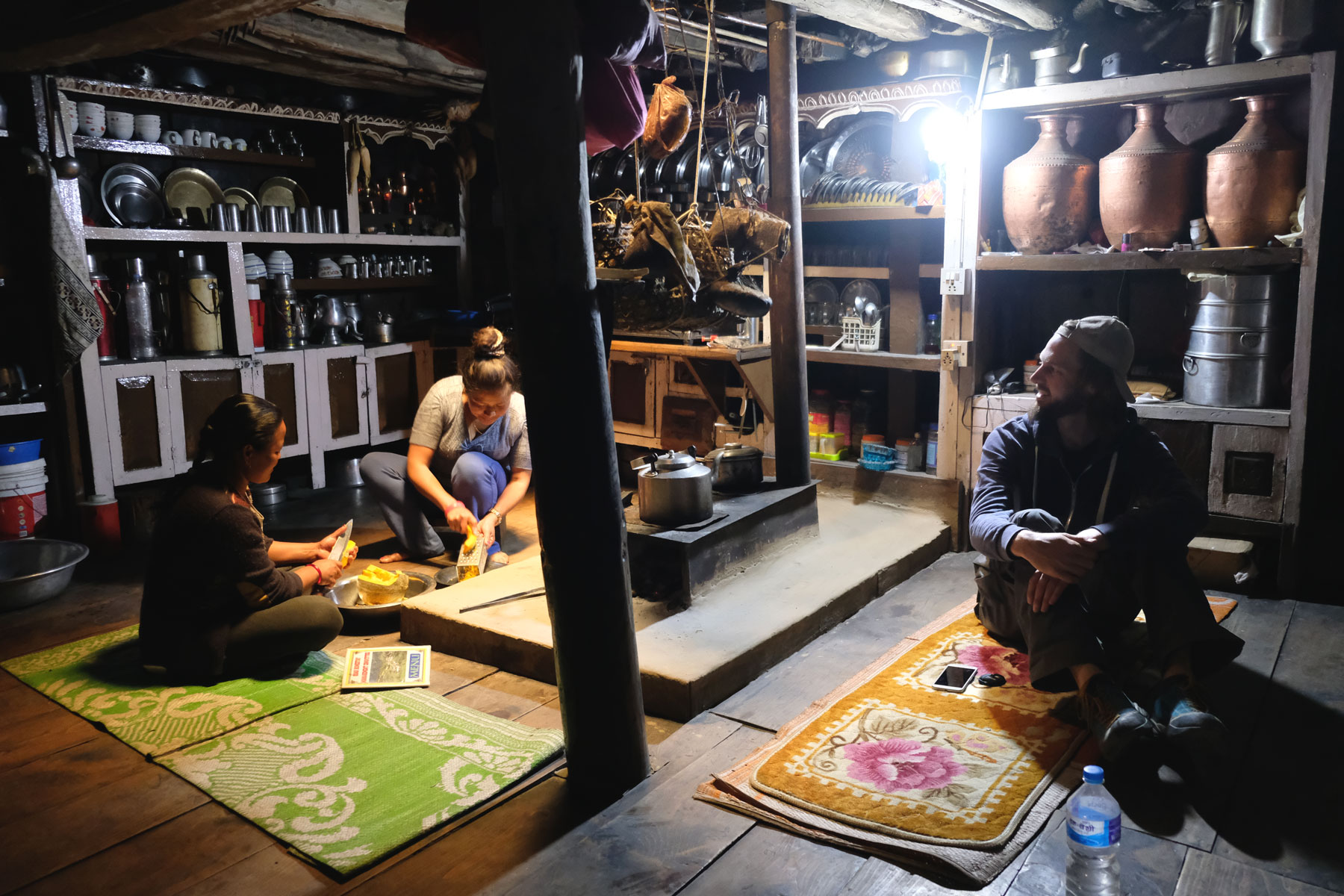 Sebastian sitzt mit zwei Frauen in einem traditionellen Haus in Odar auf dem Annapurna Circuit.