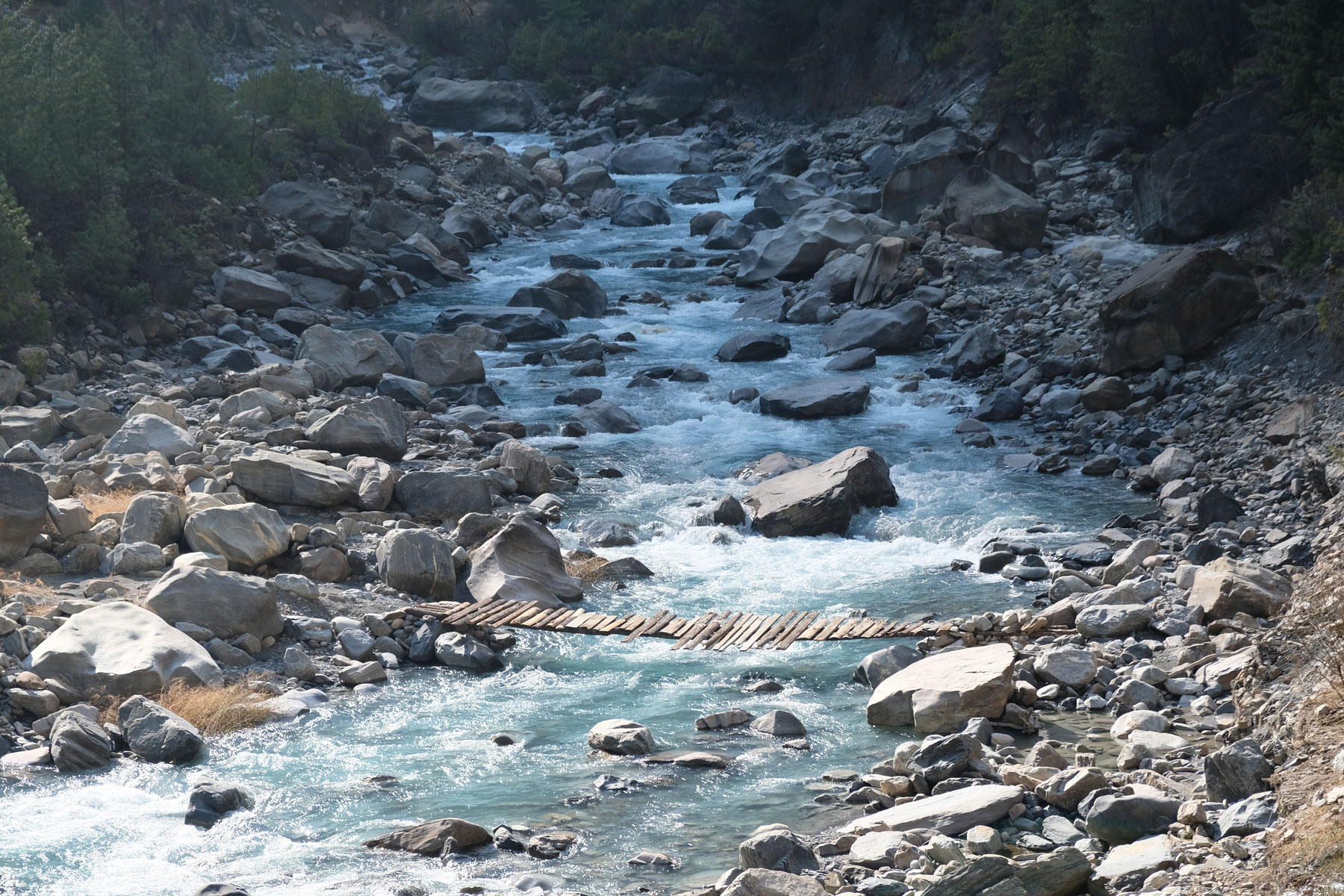 Eine einfache Holzbrücke über einem Fluss.