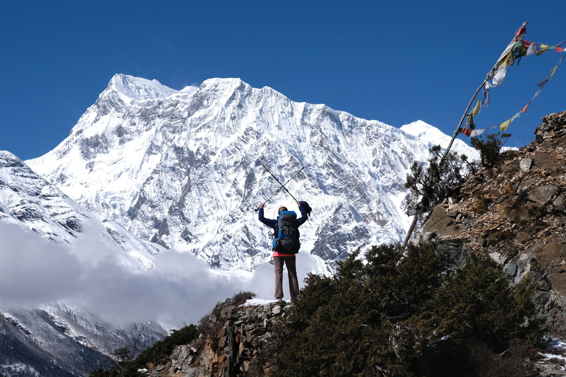 Leo streckt vor einem schneebedeckten Berg im Annapurnagebirge Wandersöcke in die Höhe.