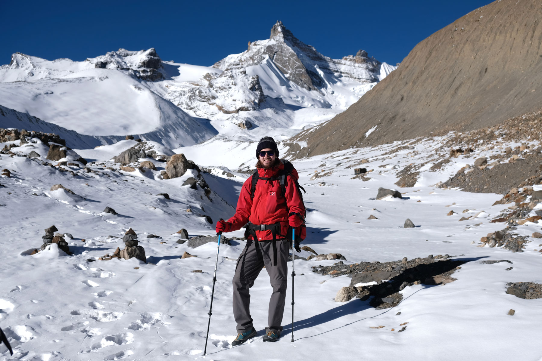 Sebastian mit Wanderstöcken auf schneebedeckten Bergen des Annapurna Circuit.