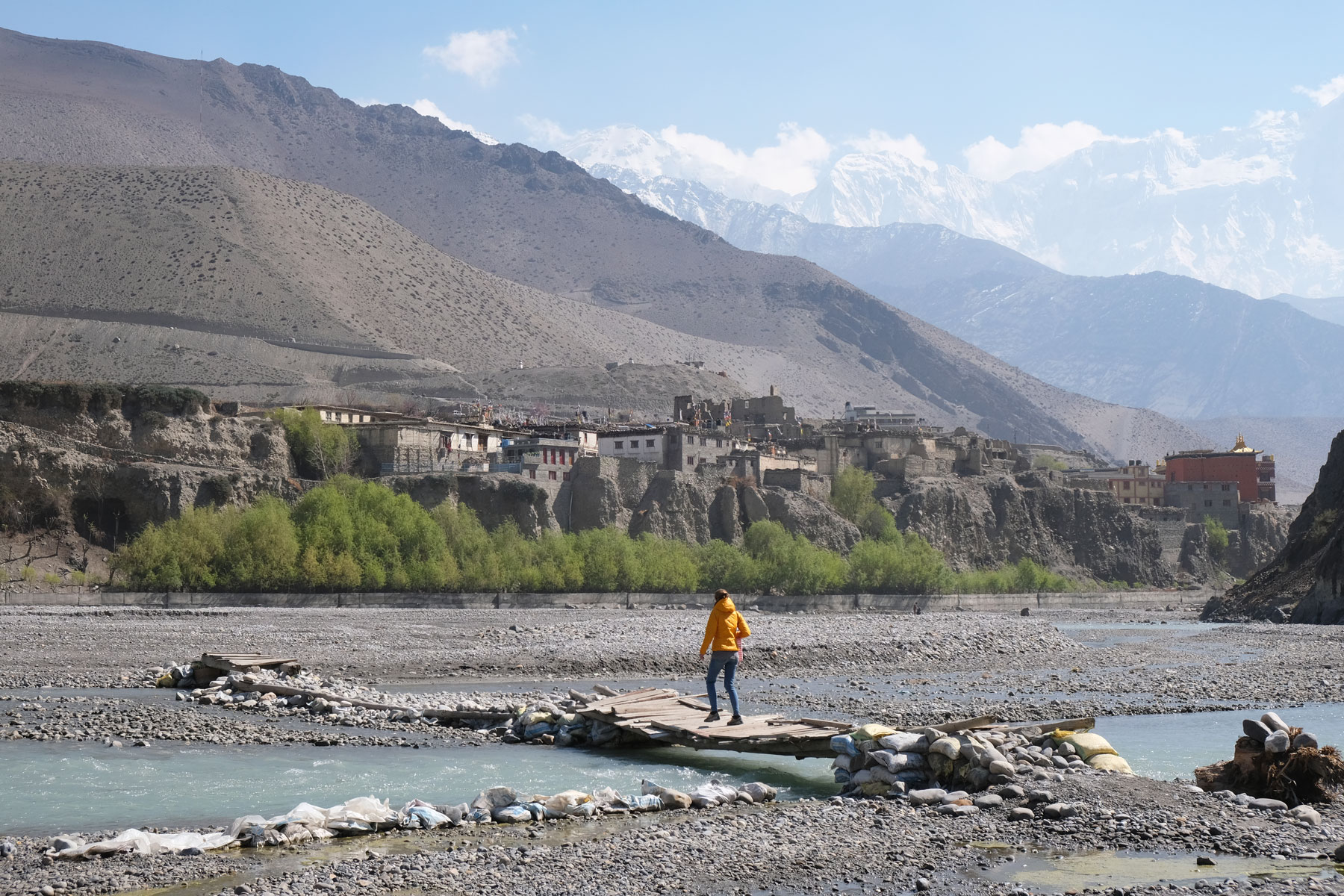 Leo geht im Flussbett des Kali Gandaki über eine schmale Holzbrücke.