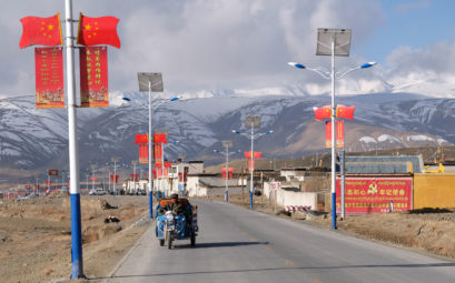 Eine mit chinesischen Flaggen gesäumte Straße in Tibet.