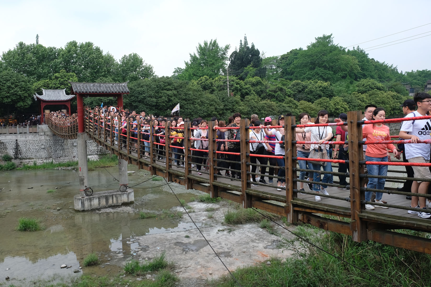 Chinesische Menschen gehen beim Bewässerungssystem von Dujiangyan über eine Hängebrücke.