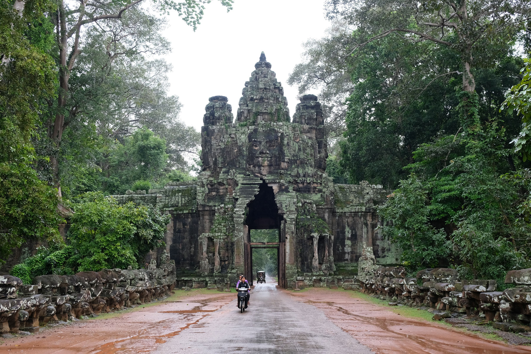 Ein Motorrad fährt durch das Victory Gate von Angkor Wat.