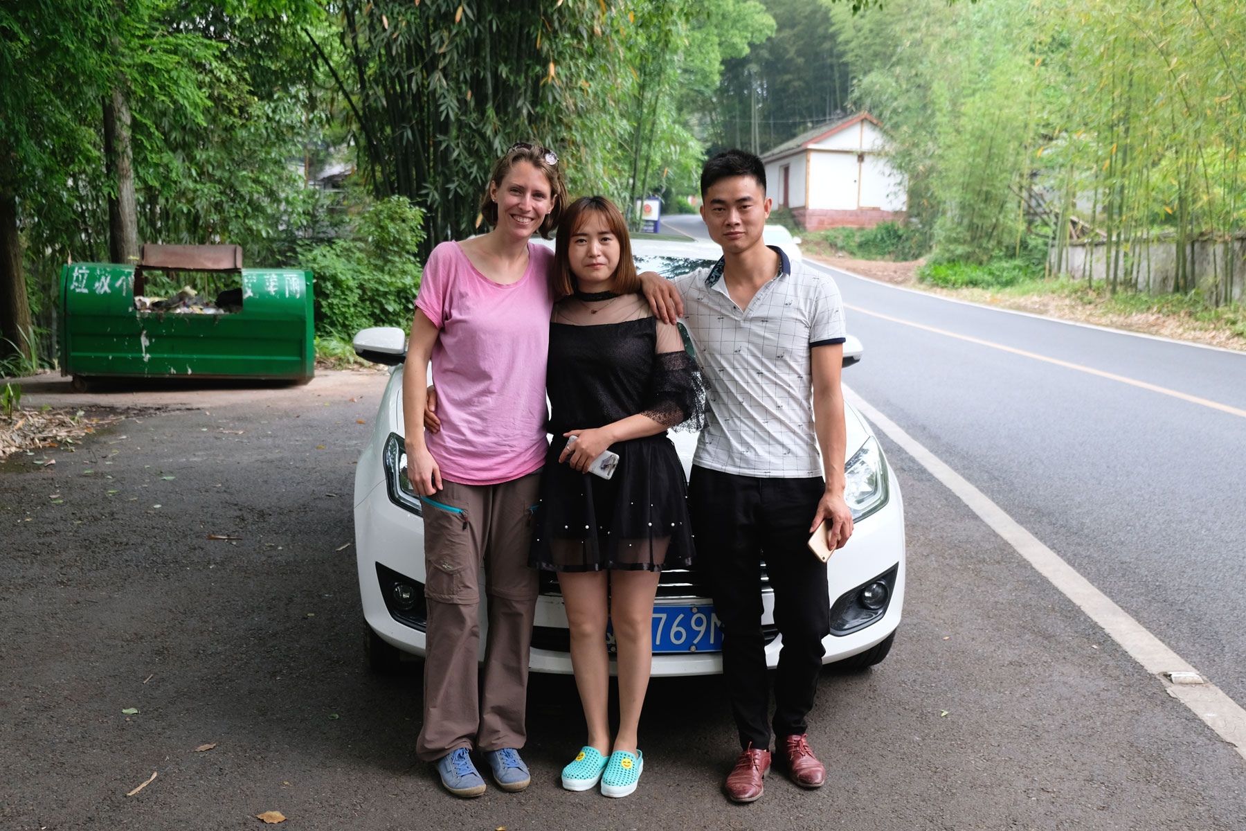 Leo steht mit einem chinesischen Pärchen vor einem Auto.