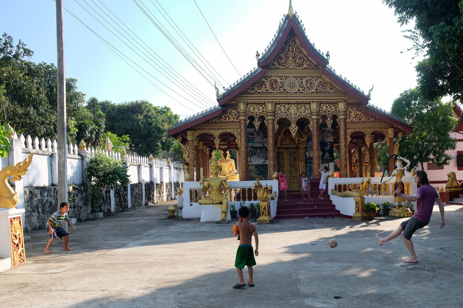 Sebastian spielt vor einem laotischen Tempel mit Kindern Fußball.