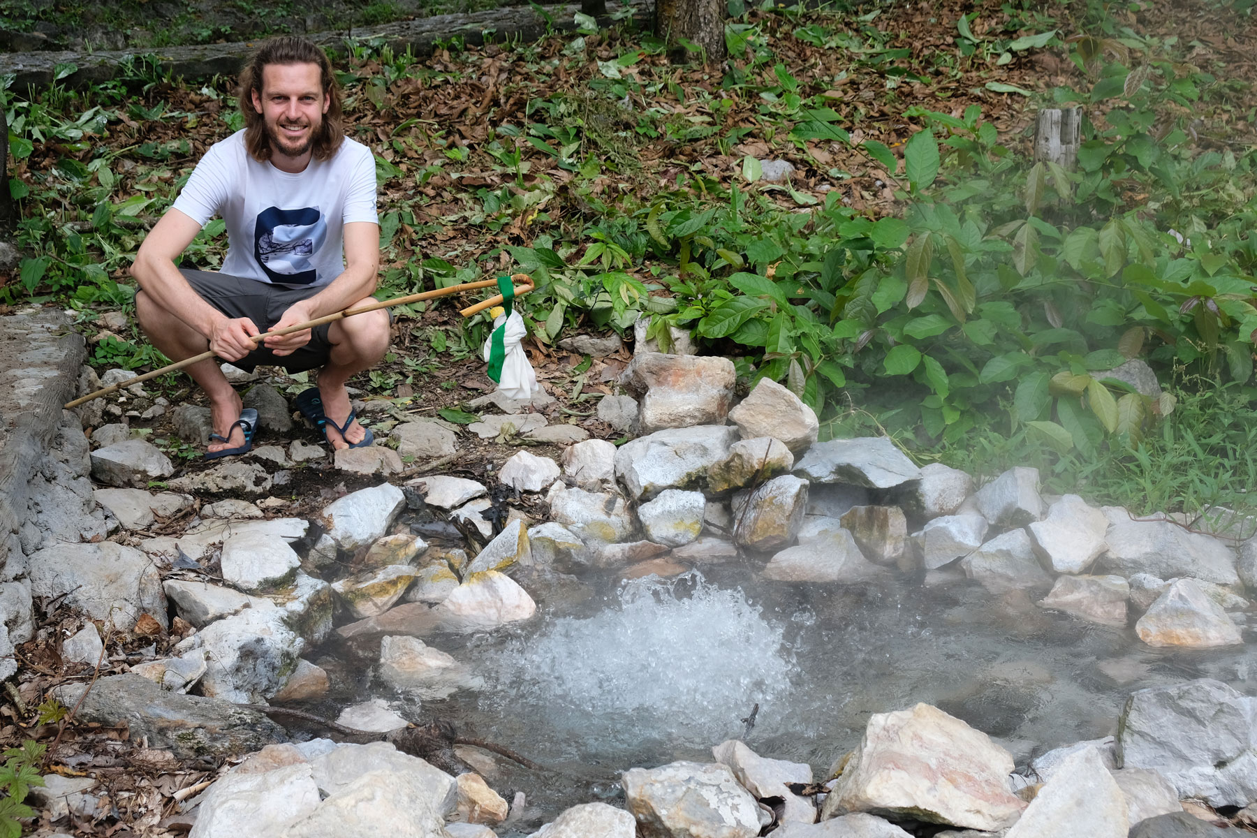 Sebastian kocht mit Hilfe eines Stoffbeutels und eines Stocks Eier im kochenden Wasser des Pong Duet Geysirs.