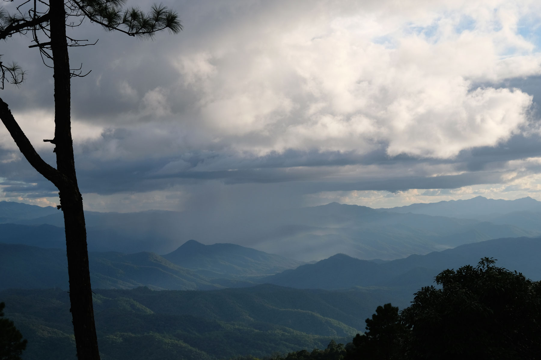 Dunkle Regenwolken ziehen über die Berge eines thailändischen Nationalparks.
