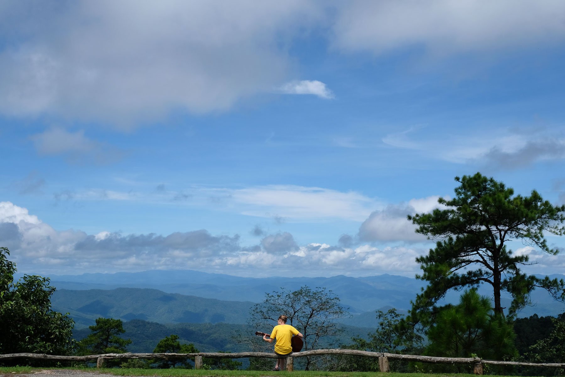 Leo sitzt Gitarre spielend vor dem Bergpanorama eines thailändischen Nationalparks.