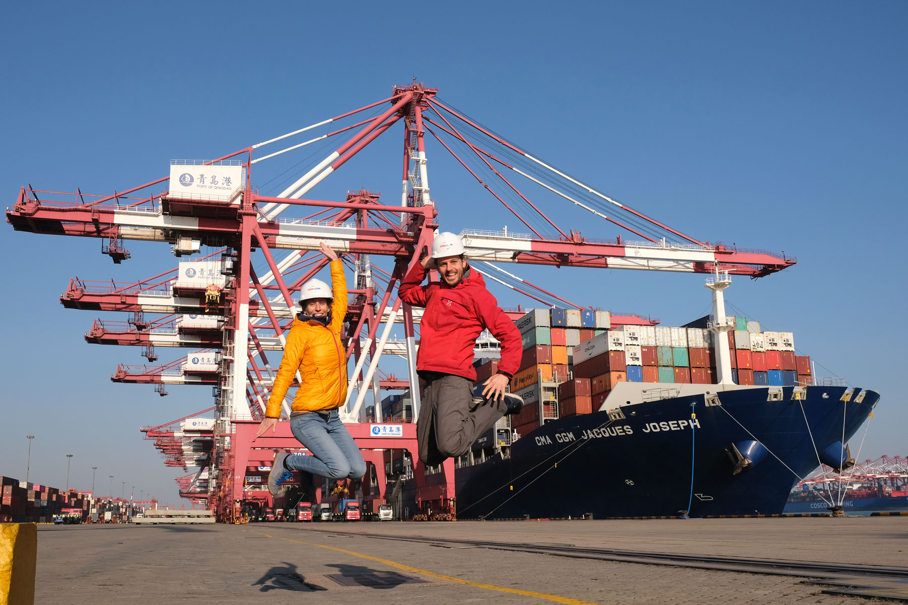 Leo uns Sebastian springen am Hafen von Qingdao vor dem Containerschiff Jacques Joseph in die Luft.