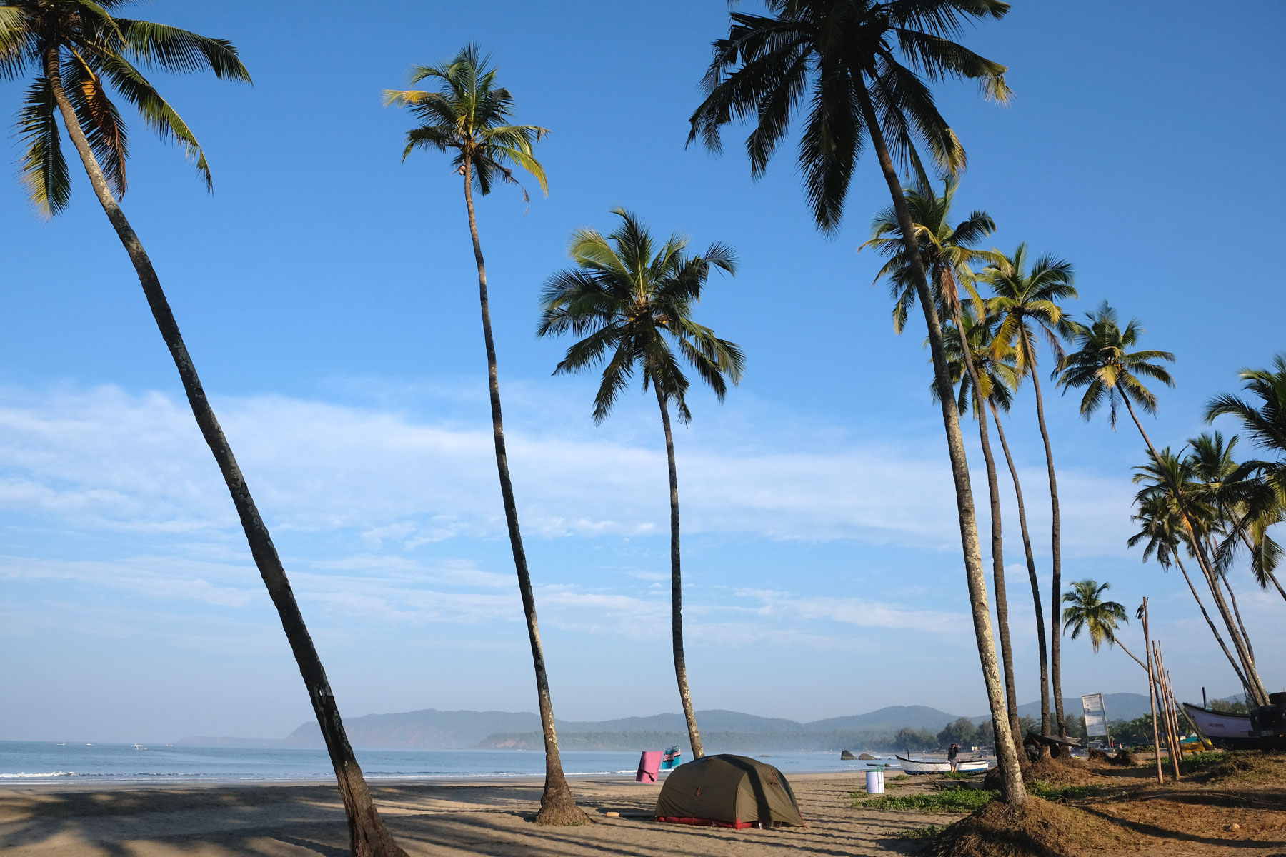 Ein Zelt unter Kokospalmen am Strand von Agonda in Goa in Indien.