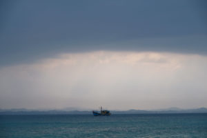 Ein Schiff schaukelt unter dunklen Wolken auf dem Meer