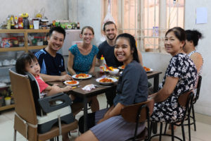 Leo und Sebastian sitzen mit ihren vietnamesischen Couchsurfing-Gastgebern am Esstisch.