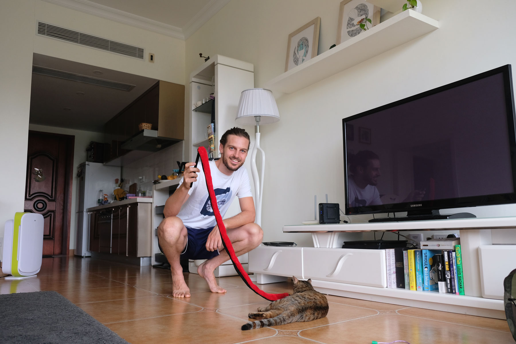 Sebastian spielt beim House Sitting in China mit einer Katze im Wohnzimmer.