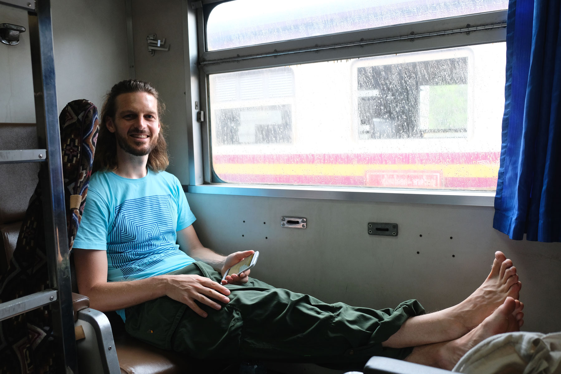 Sebastian sitzt gemütlich im Zug der thailändischen Bahn auf dem Weg nach Bangkok.