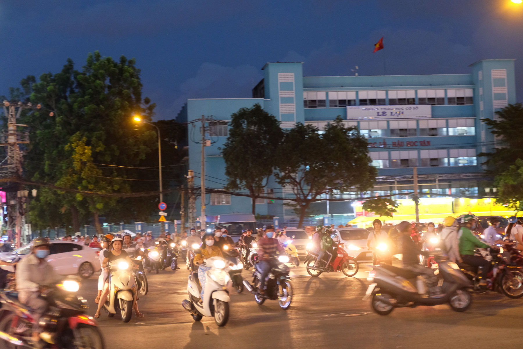 In der Dunkelheit fahren hell beleuchtete Motorroller durch die Innenstadt von Ho-Chi-Minh-City in Vietnam.