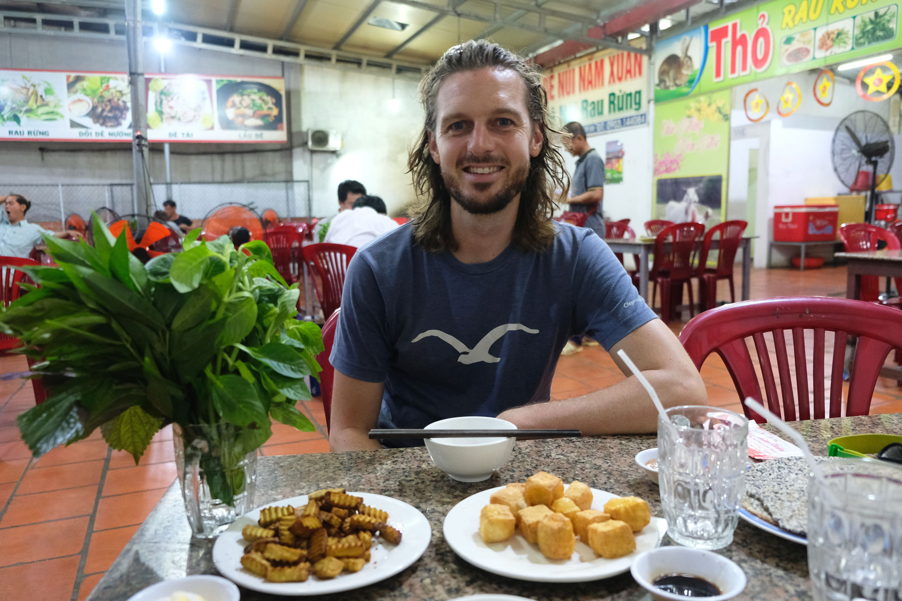 Sebastian sitzt vor zwei Tellern Tofu und Taro, unserem Abendessen.