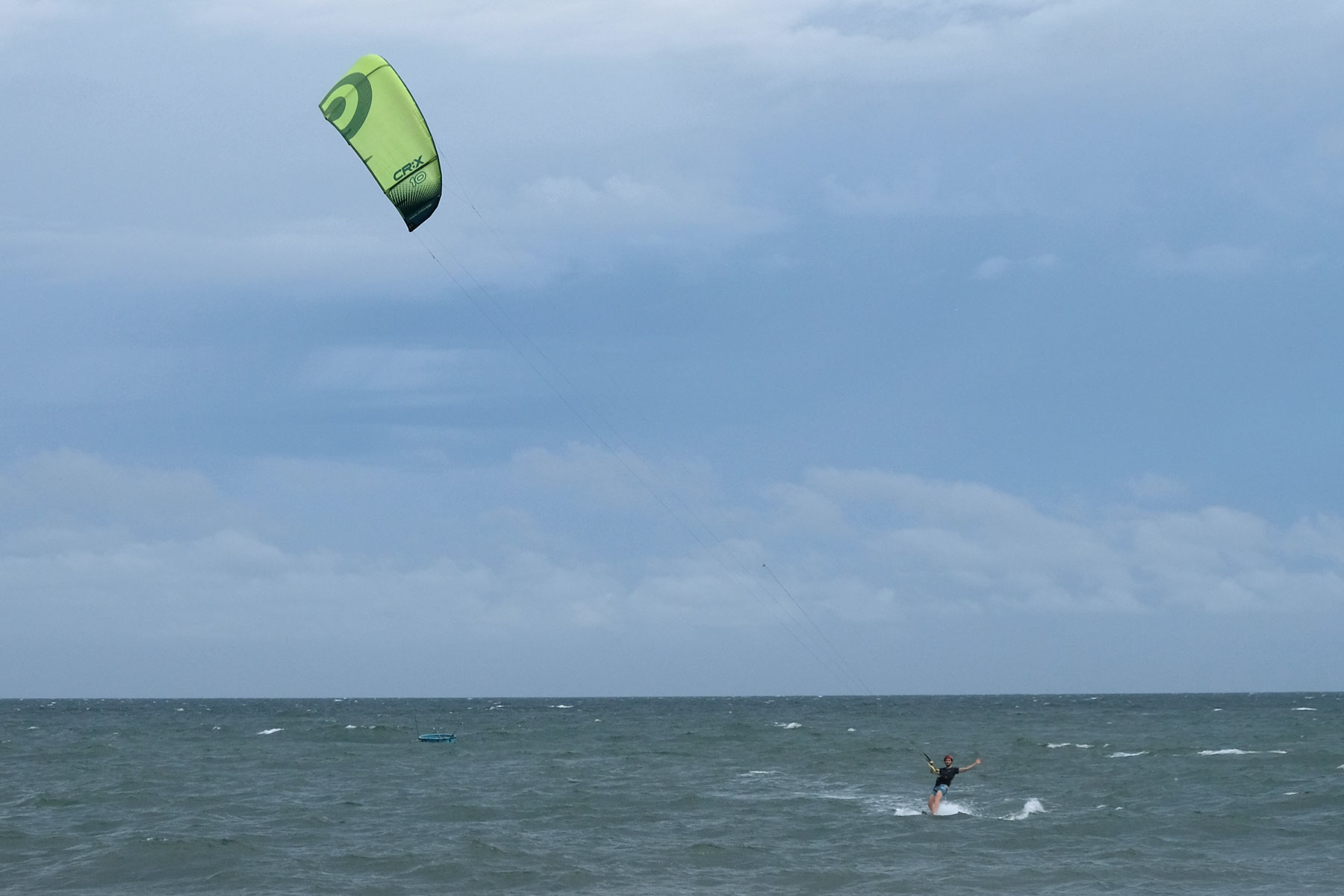 Sebastian fährt auf einem Kiteboard über das Meer vor Mui Ne in Vietnam.