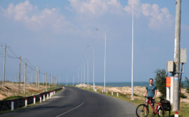 Sebastian steht mit seinem Fahrrad an der ruhigen Küstestraße im Süden Vietnams.