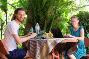 Leo und Sebastian arbeiten an ihren Laptops in Thailand im Garten ihres Hostels.