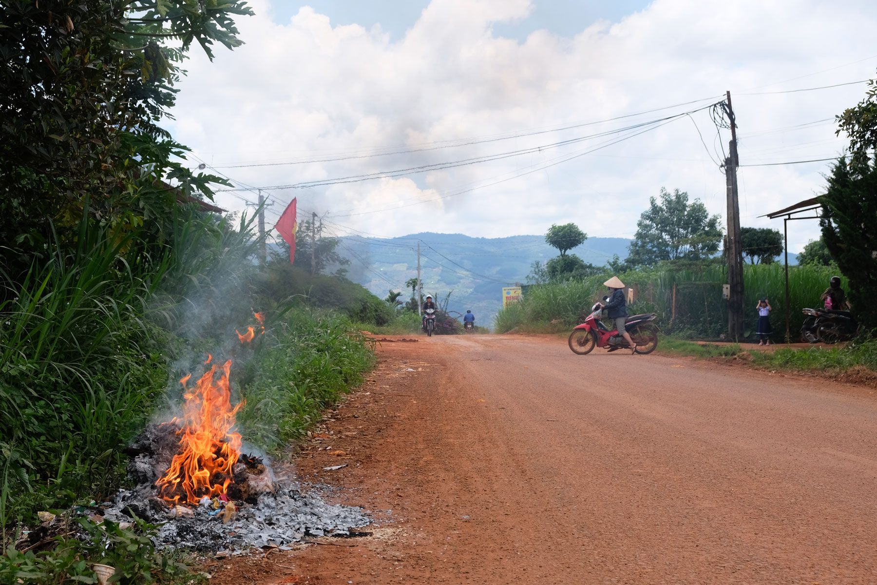 Auf einer kleinen Straße wird Plastikmüll im Feuer verbrannt.