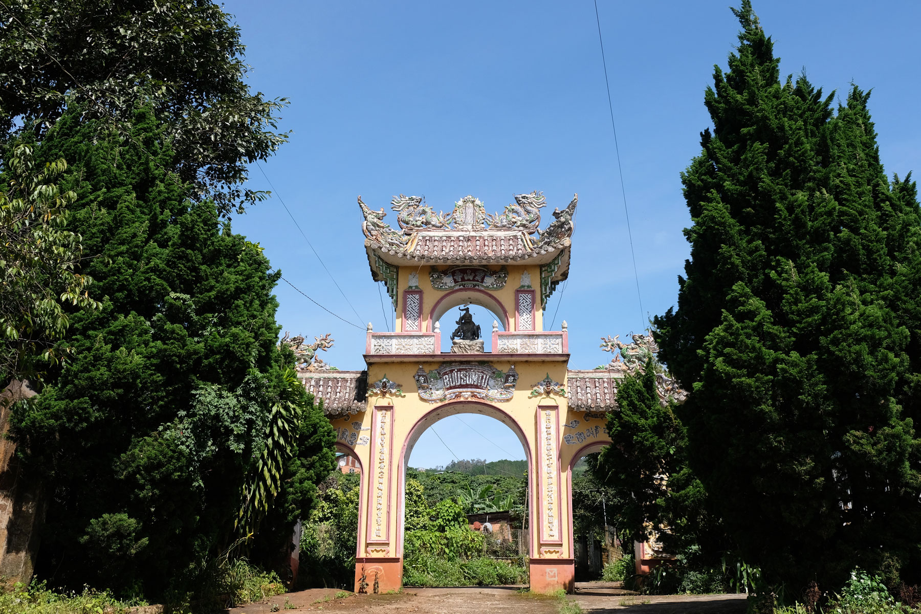 Ein vietnamesisches Tor steht zwischen zwei großen Bäumen.