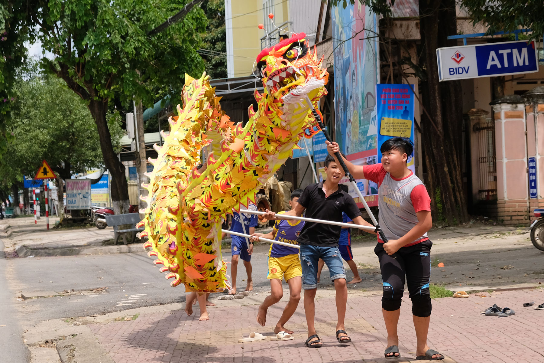 Jungen balancieren einen großen Papierdrachen auf langen Stöcken in Vietnam.