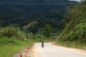 Leo kämpft sich mit ihrem Fahrrad den Berg im Hochland Vietnams hinauf.