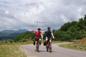 Leo und Sebastian fahren mit ihren Fahrrädern auf einer Straße im Hochland Vietnams.