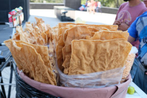Verkäufer bieten große Platten von Chicharon an.