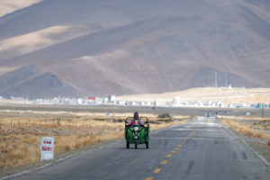 Ein Mann fährt auf seinem Dreirad über den leeren Friendship Highway zwischen Nepal und Tibet.