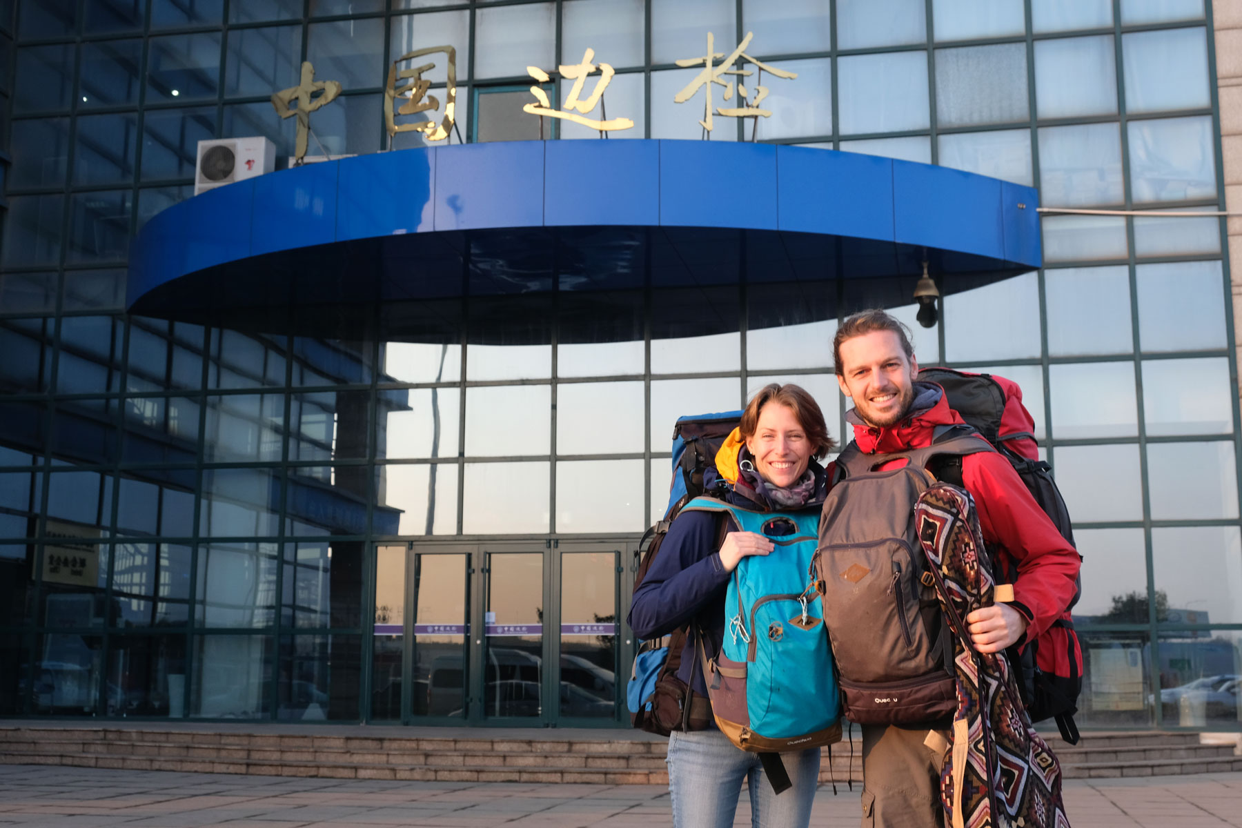 Leo und Sebastian mit Gepäck vor dem Ausreisegebäude am Hafen von Qingdao.